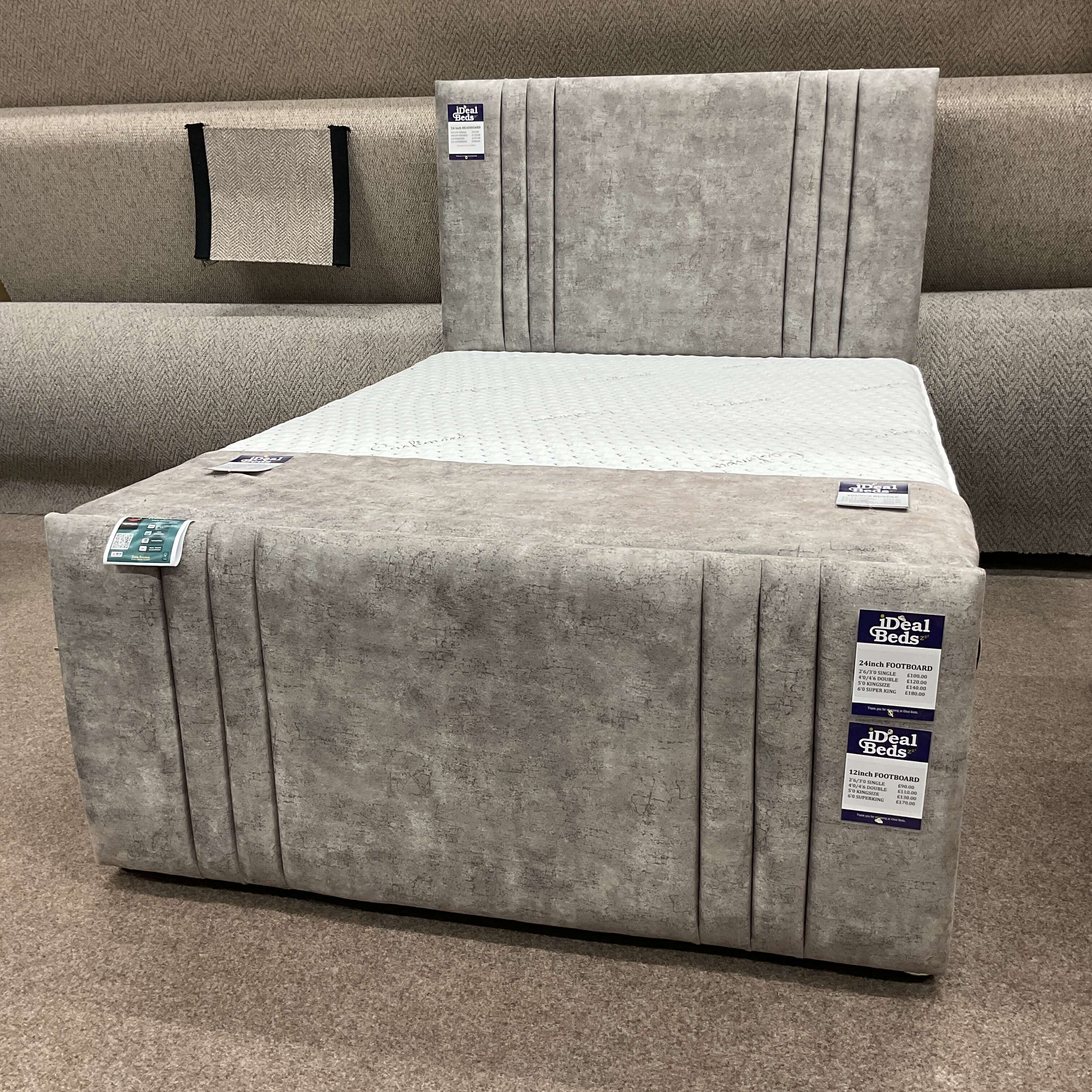 Grey upholstered divan bed with matching headboard and footboard on display at Ideal Beds in Chesterfield.