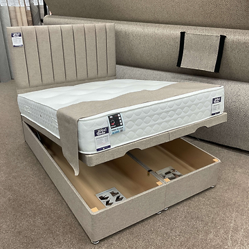 Beige ottoman bed partially lifted to show twin storage compartments at Ideal Beds Chesterfield.